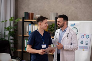 Two young male doctors talking in the staffrrom clipart