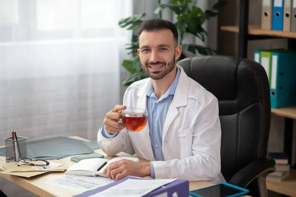 Koyu saçlı, sakallı, beyaz cüppeli doktor kendini iyi hissediyor. — Stok fotoğraf