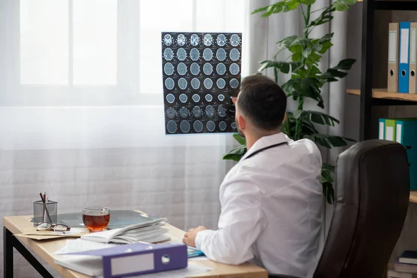 Young bearded doctor in a white robe working in his office