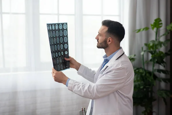 Jovem médico barbudo em um manto branco analisando os resultados da RM — Fotografia de Stock