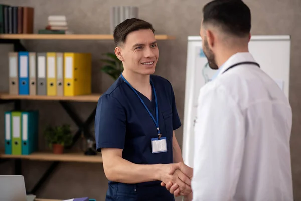 Joven pasante masculino buscando alegre mientras se reúne médico jefe — Foto de Stock