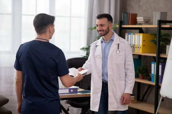 Médico jefe barbudo estrechando la mano con un joven interno — Foto de Stock