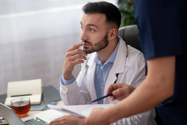 Brodaty lekarz w białym szlafroku wyglądający troskliwie — Zdjęcie stockowe