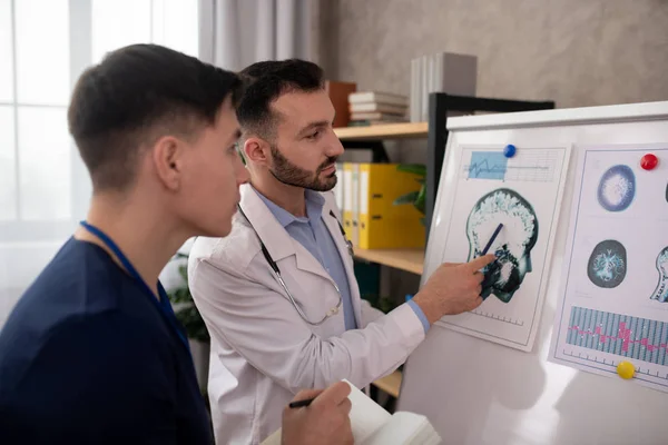 Två unga neurologer tittar koncentrerat medan de diskuterar det medicinska fallet — Stockfoto