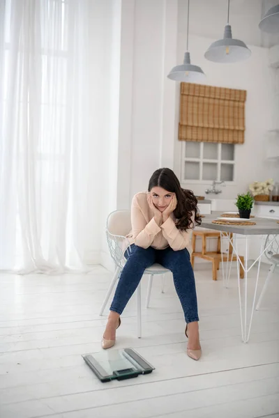 Young woman in a beige blouse sitting and feeling frustrated — Stock fotografie