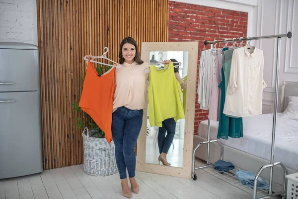 Jovem mulher em uma blusa bege tentando roupas novas — Fotografia de Stock