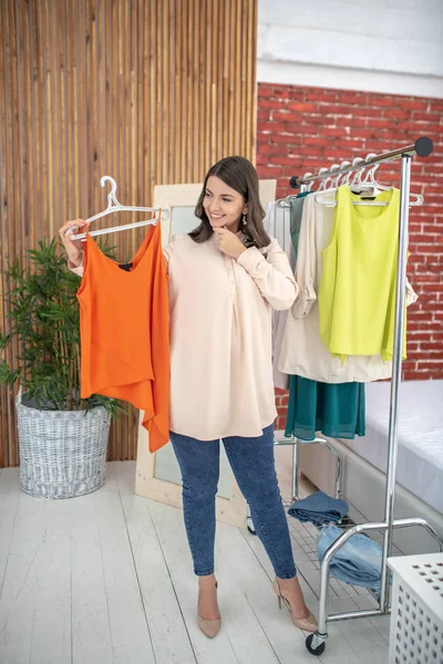 Young woman in a beige blouse trying a new shirt — Φωτογραφία Αρχείου