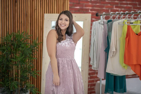 Jovem mulher plus-size em um vestido rosa de pé em uma loja de roupas — Fotografia de Stock