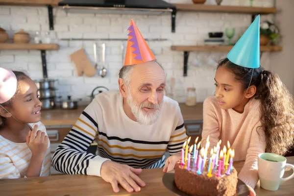 Бородач в шляпе на день рождения празднует день рождения с внучками — стоковое фото