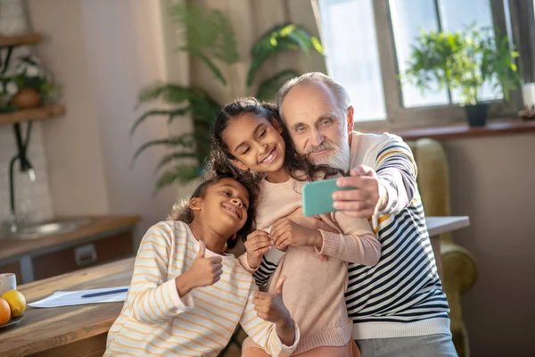 Сіроокий бородатий чоловік і його онуки виглядають щасливими — стокове фото