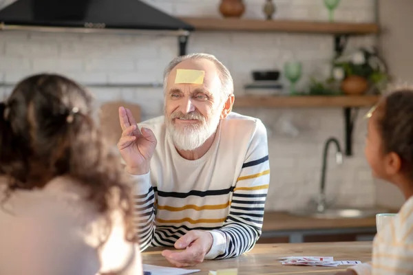 Grey-haired man playing guess game with his granddaughters — Stock Photo, Image