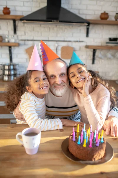 Barbudo hombre de pelo gris y sus chicas de piel oscura celebrando el bithday —  Fotos de Stock