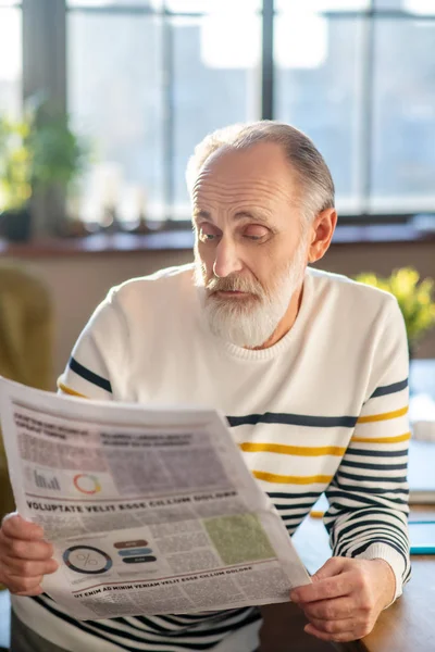 Šedovlasý vousatý muž v pruhovaném svetru pochybovačně — Stock fotografie