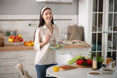 Elinde çatal ve tabakla duran genç bir kız..