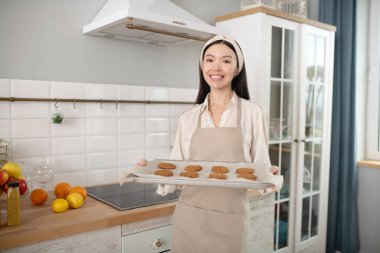 Elinde yemek çarşafı olan gülümseyen genç bir kadın..
