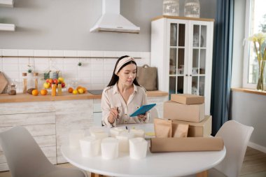 Tabletli genç bir kadın masanın yanında oturuyor..