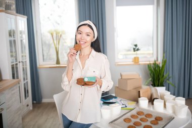 Elinde bir tabak kurabiyeyle duran ince bir kadın..