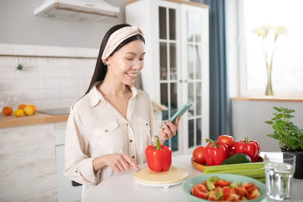 Junges Mädchen mit Kopfverband sitzt mit Smartphone. — Stockfoto