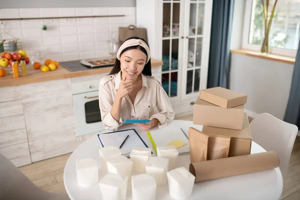 Jovencita exitosa con smartphone sentada cerca de la mesa . — Foto de Stock