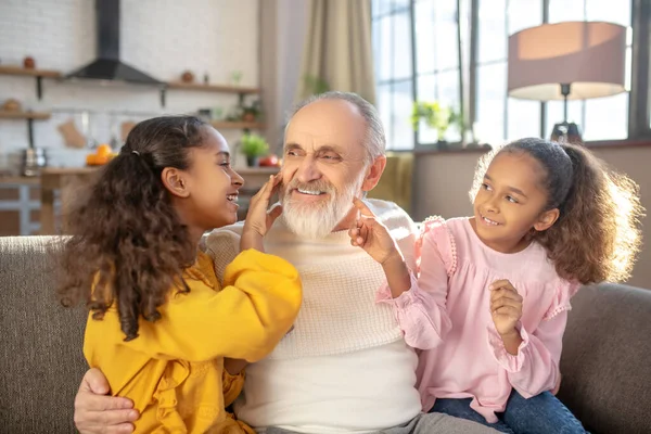 Barbuto uomo dai capelli grigi in camicia bianca sensazione incredibile trascorrere del tempo con le nipoti — Foto Stock