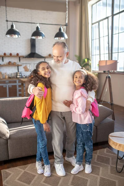 Skäggig farfar kramar sina barnbarn innan han skickar dem till skolan — Stockfoto