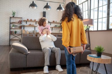 Koyu tenli tatlı kız dedesinin gözlerini kapatıyor.