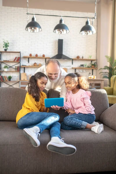 Twee donkergekleurde meisjes zitten op de bank en kijken naar een video — Stockfoto