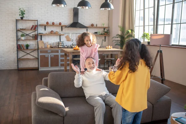 Skäggig gråhårig man som sitter på soffan och känner sig förvånad — Stockfoto