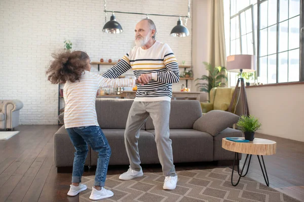 Chica de piel oscura en jeans divirtiéndose con su abuelo — Foto de Stock