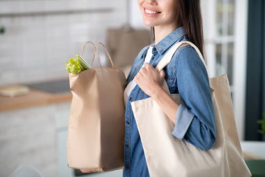 Woman with paper bag and fabric bag on his shoulder. clipart