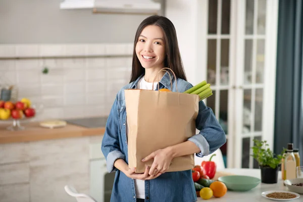 Joven mujer bonita de pie en la cocina con una bolsa ecológica . — Foto de Stock