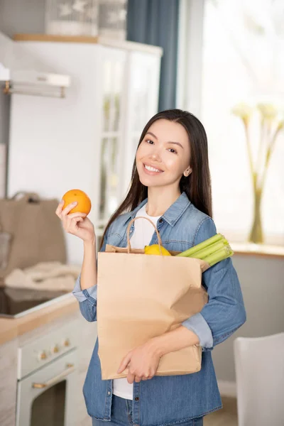 Framgångsrik ung kvinna med förpackning med grönsaker och apelsin. — Stockfoto