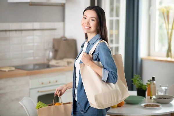 Mujer joven sonriente con bolsas ecológicas en casa . — Foto de Stock