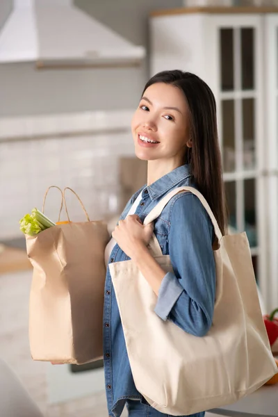 Jovem mulher asiática com eco sacos na cozinha . — Fotografia de Stock