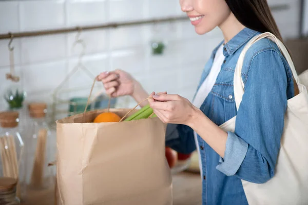 Vrouwelijke handen openen ecologische papieren zak met groenten en fruit. — Stockfoto