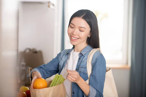 Vacker ung kvinna med papperspåse av grönsaker och frukter. — Stockfoto