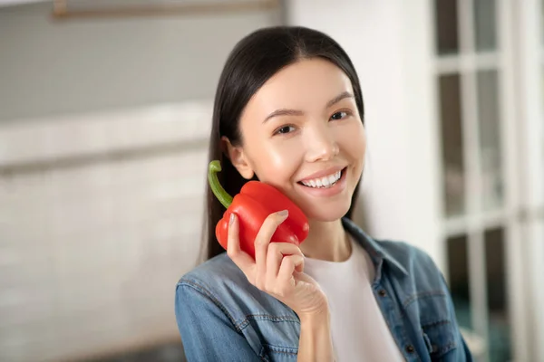 Mujer joven en chaqueta de mezclilla con pimiento dulce en la mano . — Foto de Stock