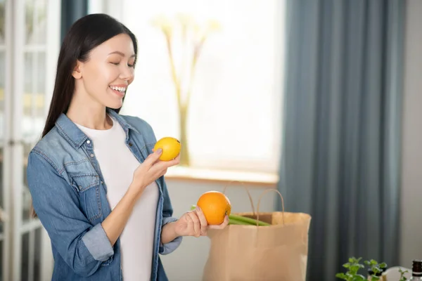 Ung flicka med mörkt hår håller citrus i händerna. — Stockfoto