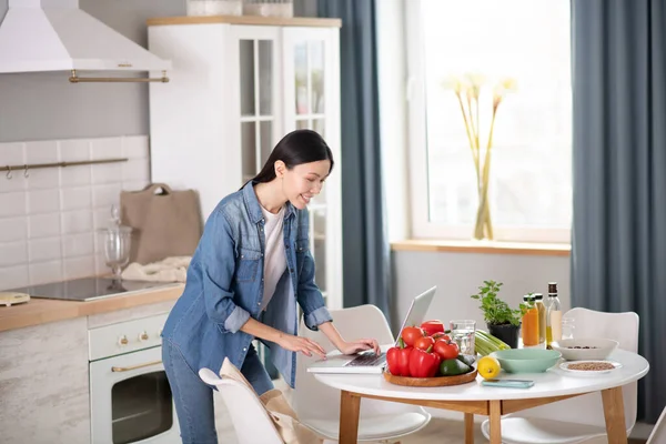 Jong meisje in de buurt van laptop, op de tafel vegetarische producten. — Stockfoto