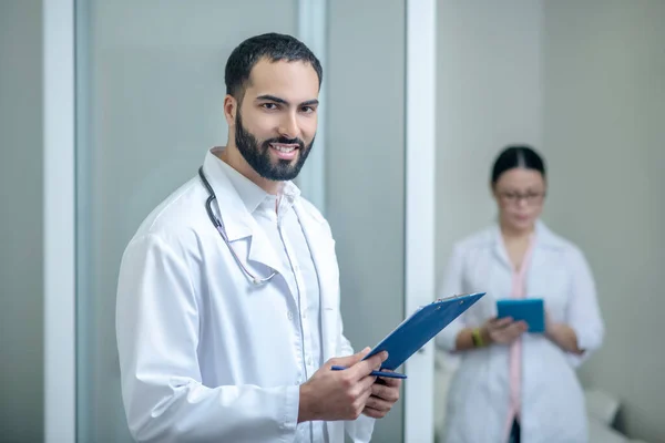 Dark-haired male and female doctors standing in the room — Stockfoto