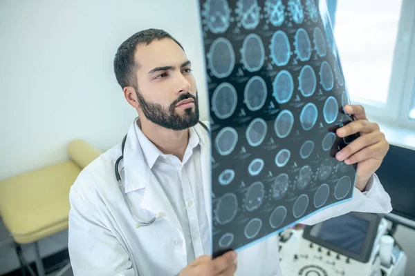 Médico barbudo masculino con bata blanca analizando los resultados de la resonancia magnética — Foto de Stock