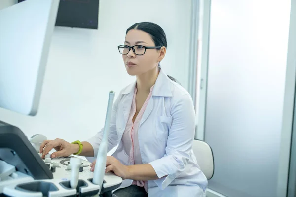 Dokter wanita memakai kacamata duduk di perangkat ultrasonik terlihat terkonsentrasi — Stok Foto