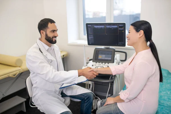 Dark-haired young doctor greeting his female patient before investigation — Stockfoto