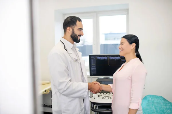 Dark-haired young doctor greeting his female patient — Stockfoto