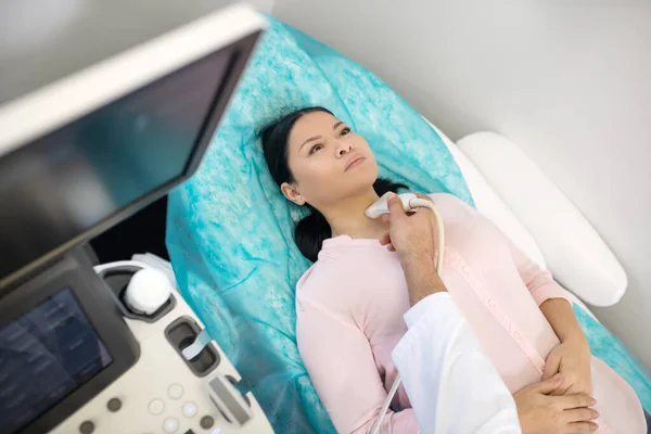 Dark-haired asian woman laying on the couch having ultrasonic investigation — 스톡 사진