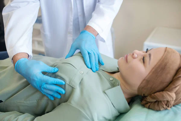 Mammologue en gants de protection bleus palpitant le sein de son patient — Photo