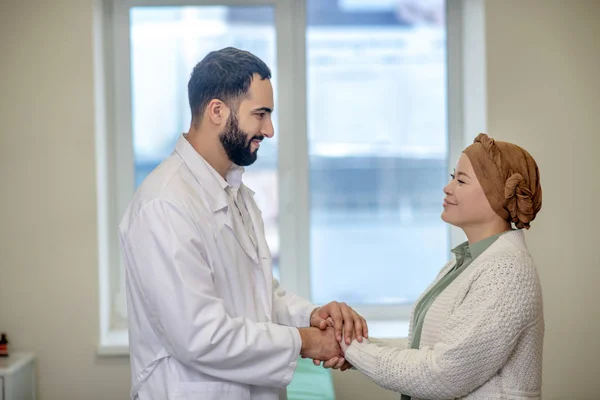 Médecin masculin tenant ses patientes mains et souriant — Photo