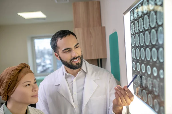 Medicul tânăr cu barbă care explică rezultatele RMN pacientului — Fotografie, imagine de stoc