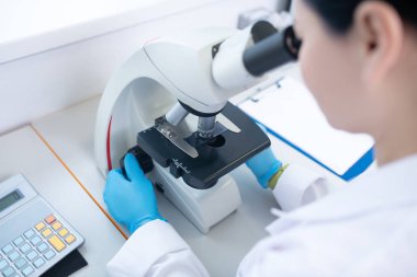 Worker of biochemical laboratory looking in microscope