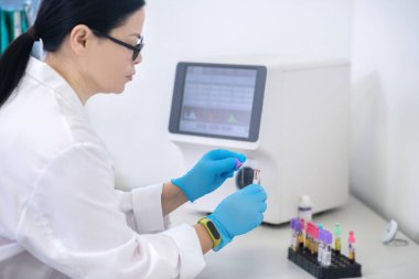 Technician in blue gloves holding samples with blood
